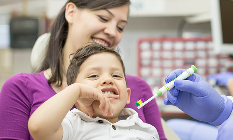 Dentist showing toothbrush to child with special needs at ManDent